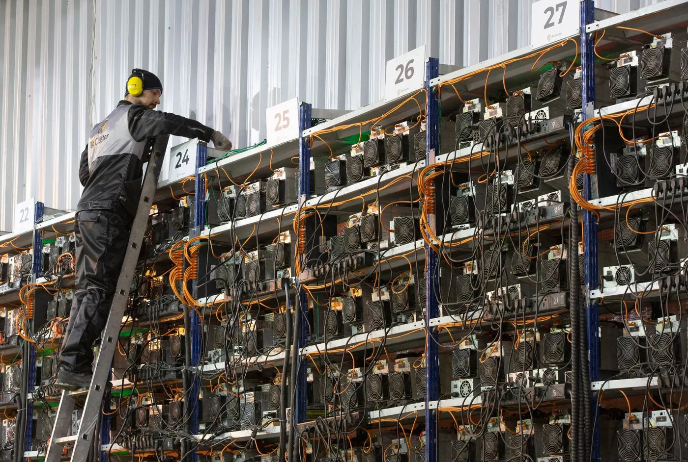 An engineer inspects racks of mining devices at a cryptocurrency mining farm in Norilsk
